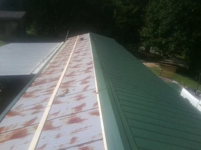 Old rusted panels beside newly installed green metal roofing — Wind Damage Roof Repair by Roofing Brothers in New Straitsville