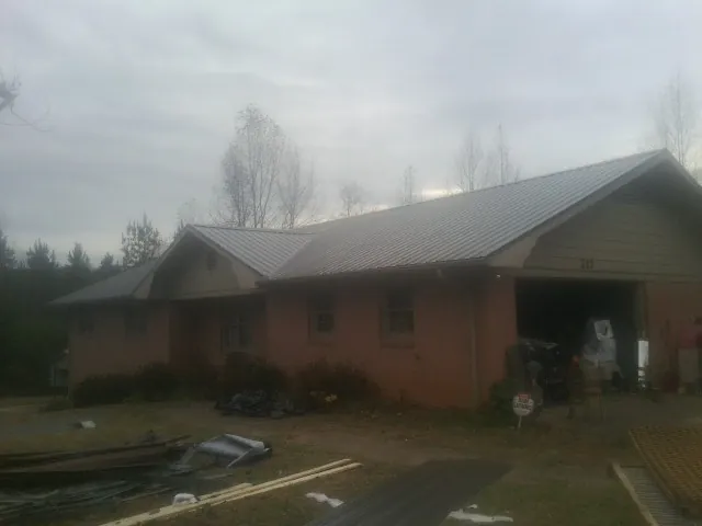Gray metal roof on a stucco house with an attached garage in New Straitsville