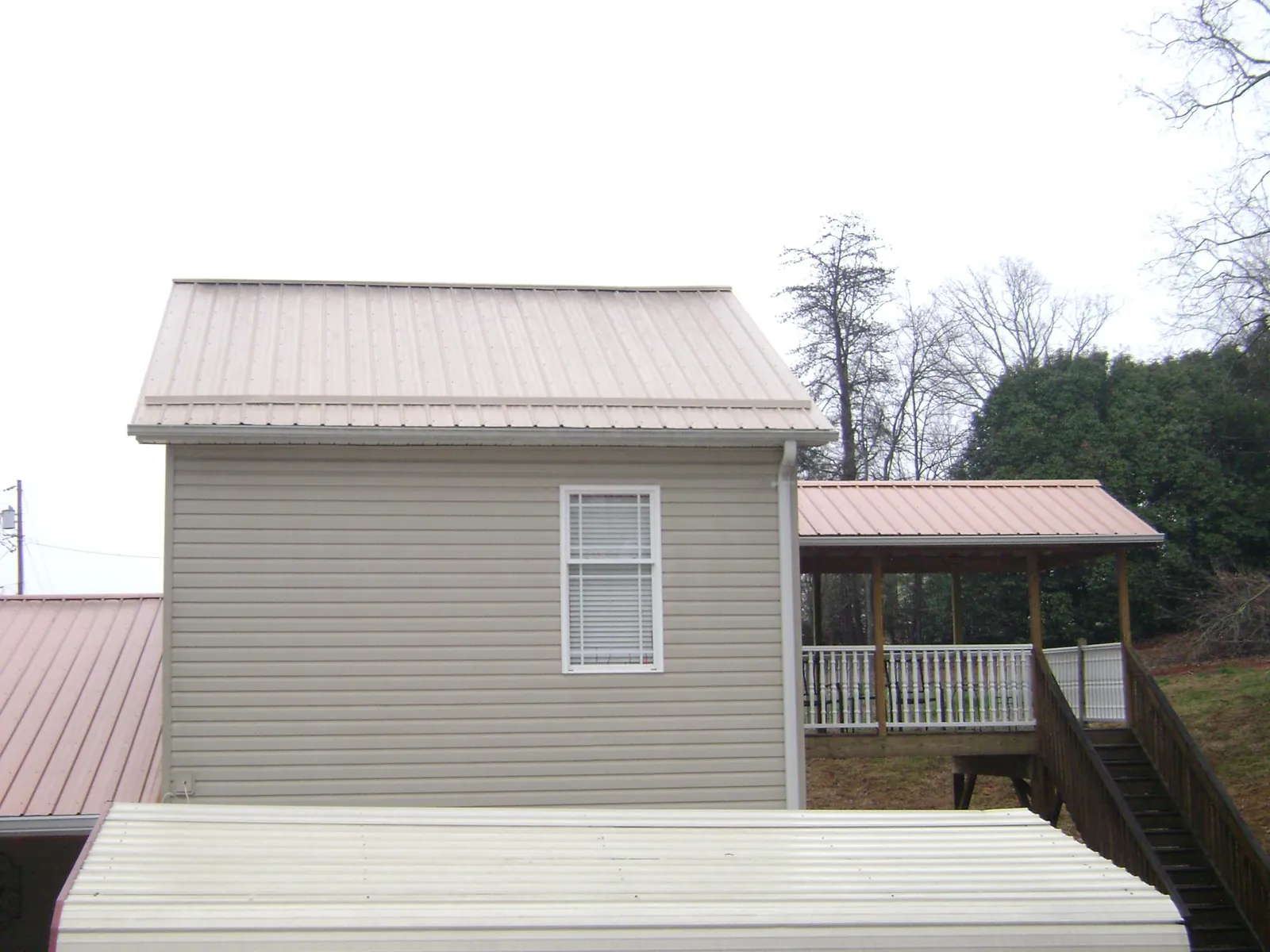 Tan metal roofs on a two story addition and attached porch, from a Roof Replacement job in New Straitsville