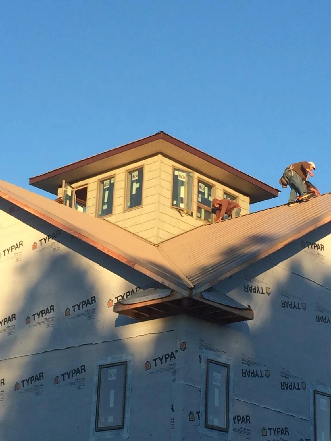Roofers working around a rooftop cupola on a new metal roof at sunset — Roof Waterproofing in New Straitsville by Roofing Brothers